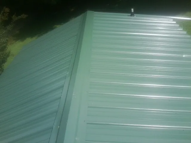 New green metal panels meeting at the ridge of a roof — Flat Roof Repair work by our crew in Slaughters