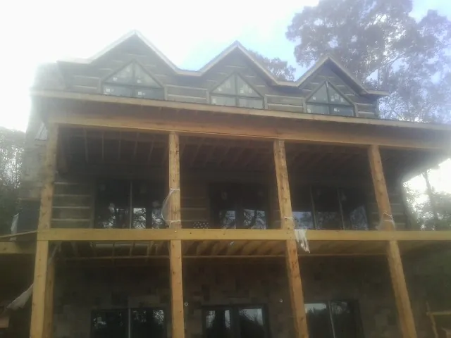 Dormers and porch framing on a large log home under construction — Roof Coating work by our crew in Slaughters