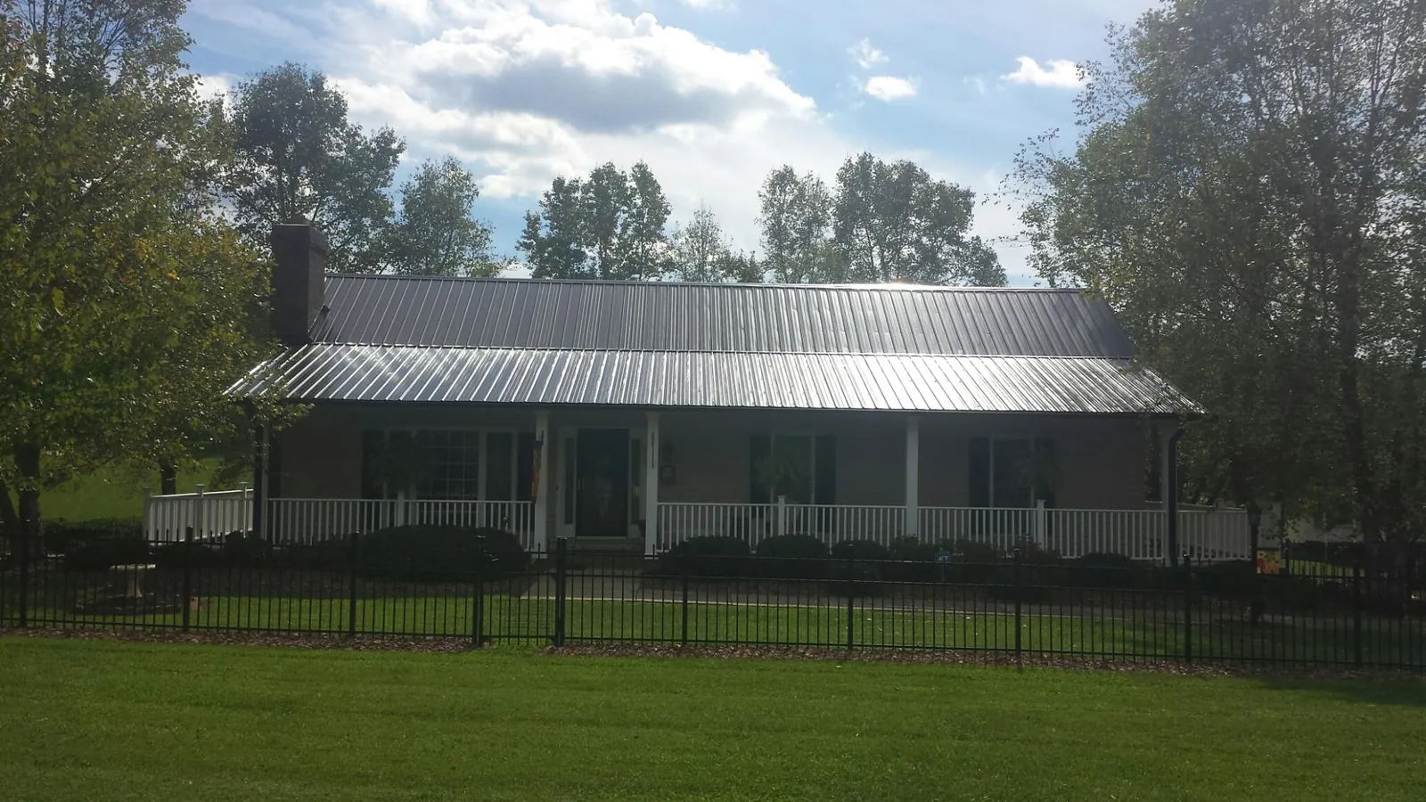 Gray metal roof on a brick ranch with a full width front porch — Gutter Guard Installation work by our crew in Slaughters
