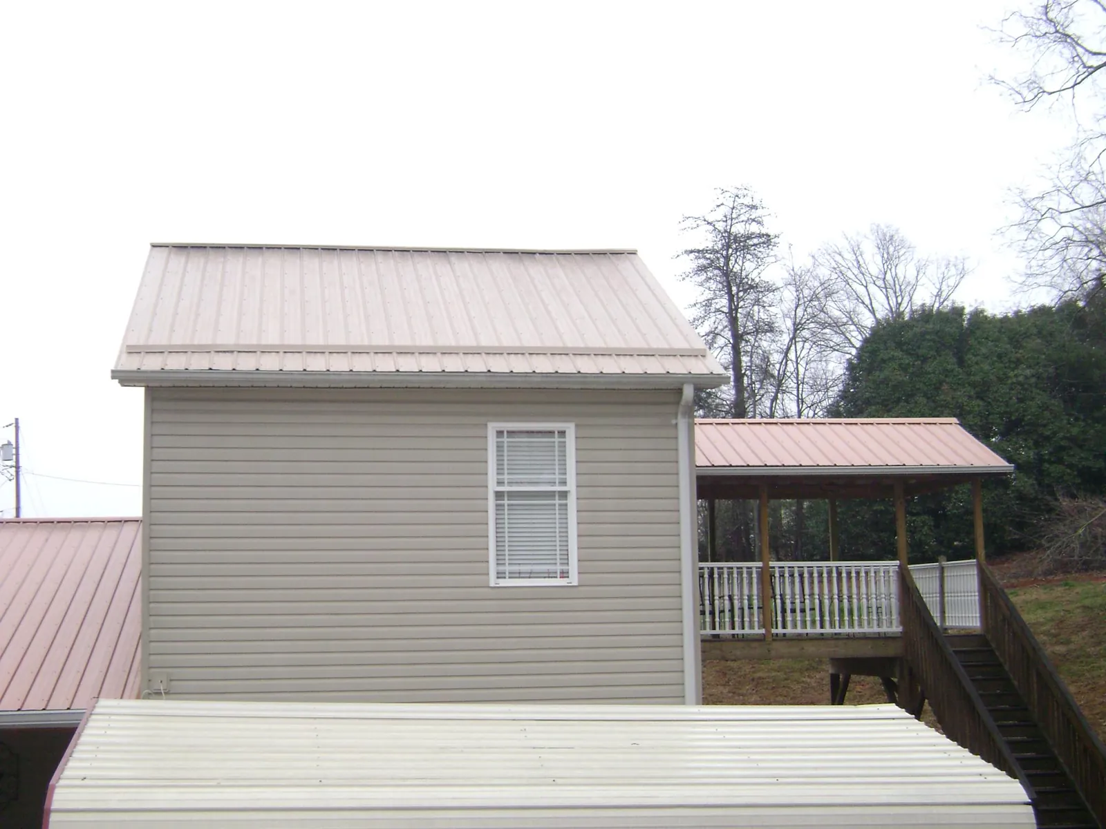 Tan metal roofs on a two story addition and attached porch, from a Roof Replacement job in Slaughters