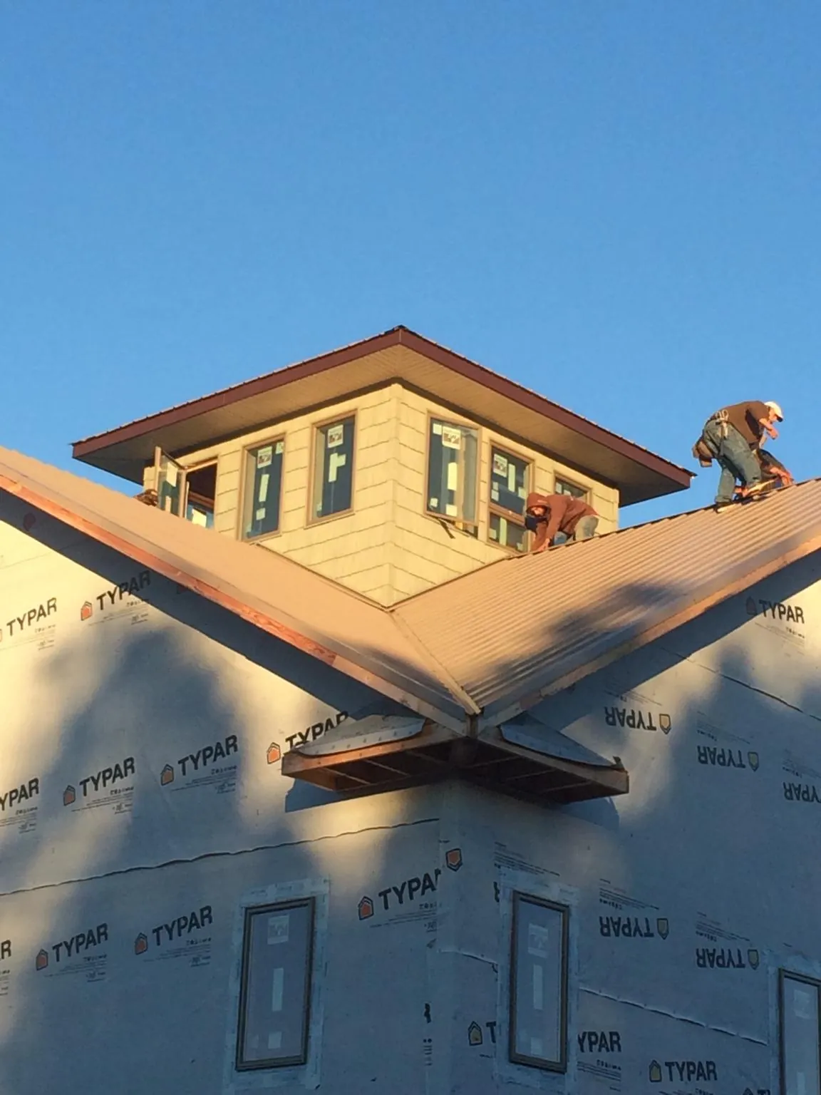 Roofers working around a rooftop cupola on a new metal roof at sunset — Roof Waterproofing in Slaughters by Roofing Brothers